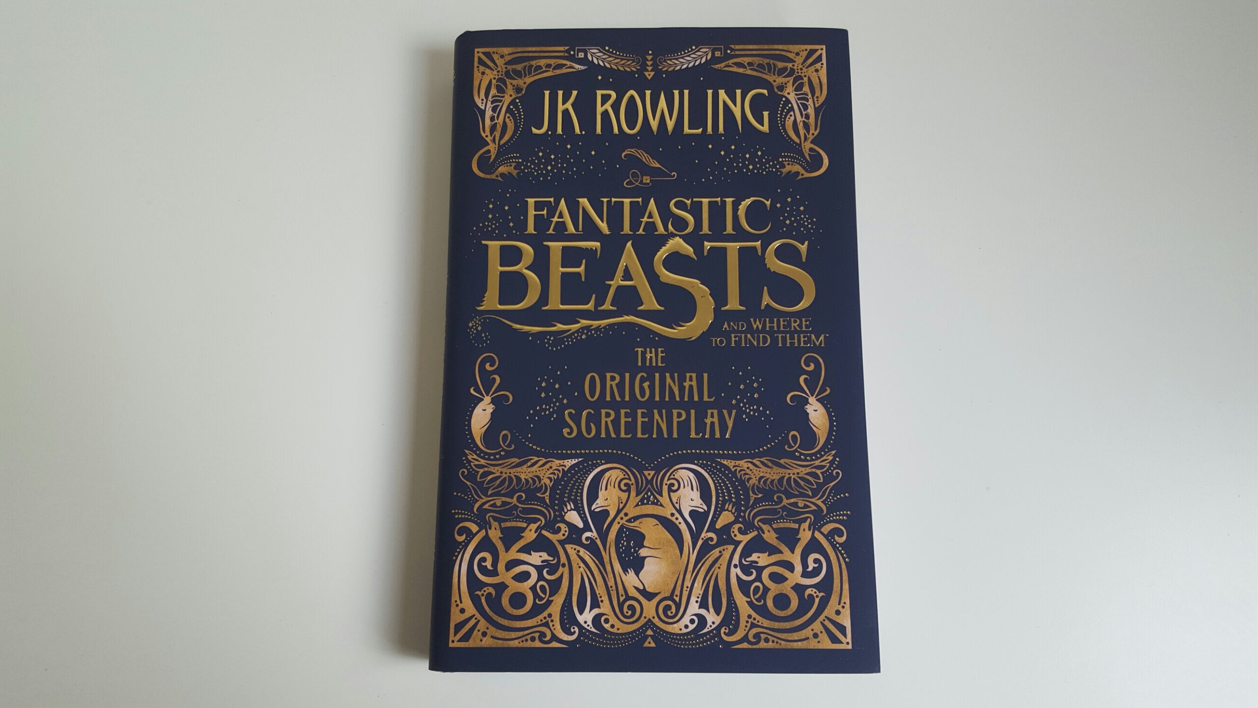 Fantastic Beasts and Where to Find Them by J. K. Rowling. The cover is a dark blue shade with gold embellishments. The title is also written in a gold color.