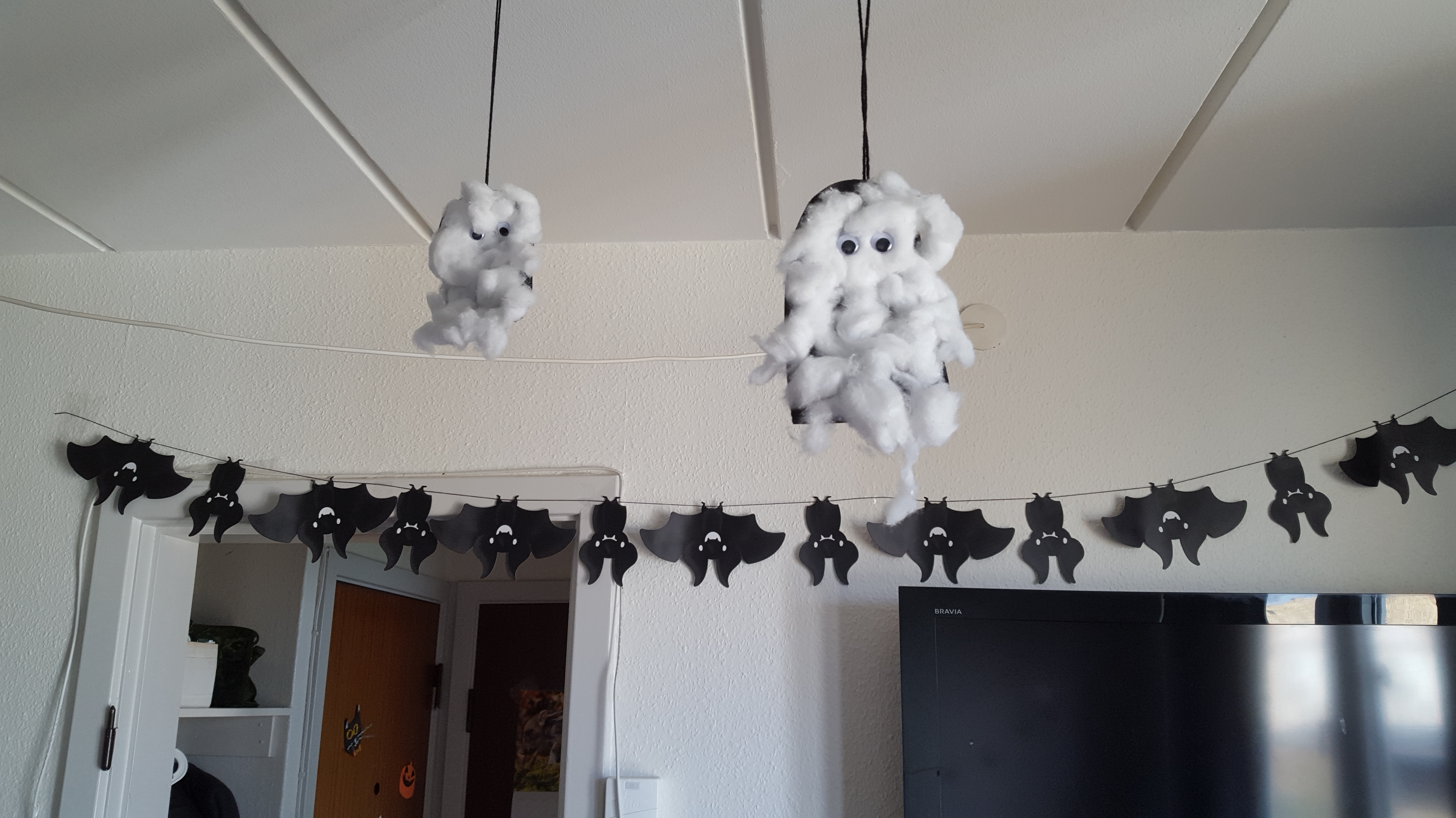 Crafted cotton ghosts hanging from the ceiling and a banner of upside down bats on the wall