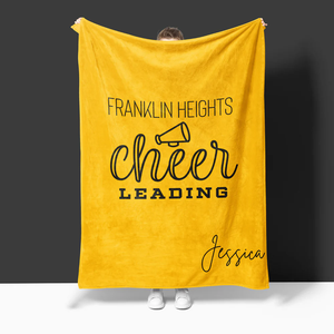 A custom blanket that is yellow and states "Franklin Heights Cheerleading" and underneath is the name Jessica.