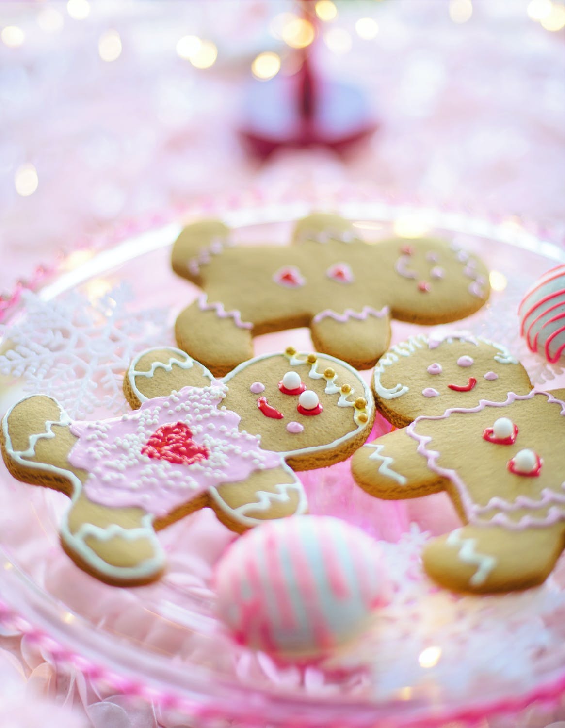 A plate of ginerbread cookies that have been decorated with pink and white icing