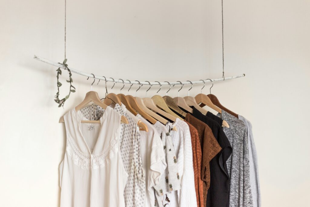 A clothing rack with shirts and sweaters hung on it.