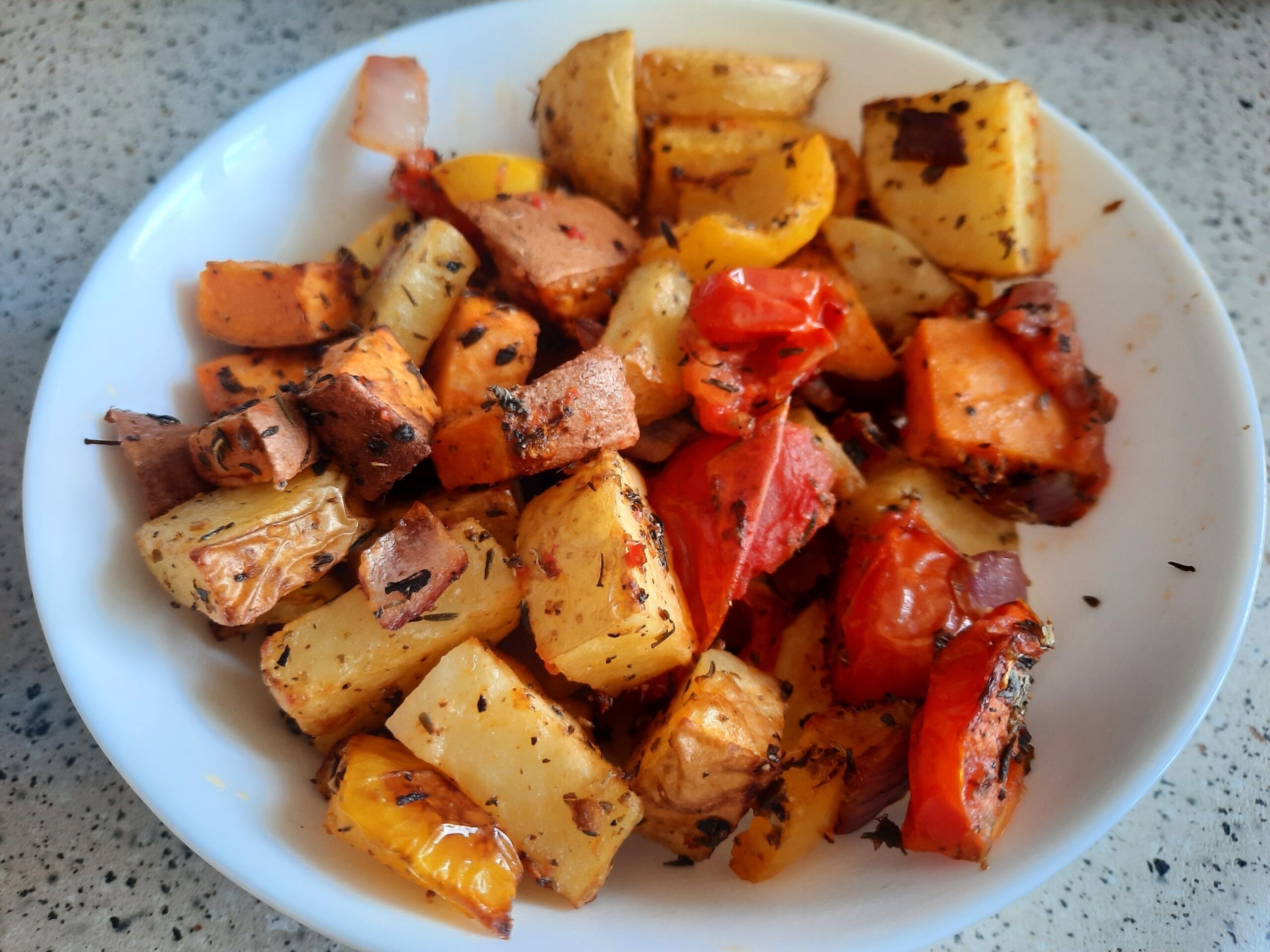 Roasted vegetables with potatoes, sweet potatoes, tomatoes, yellow bell pepper, and red onion