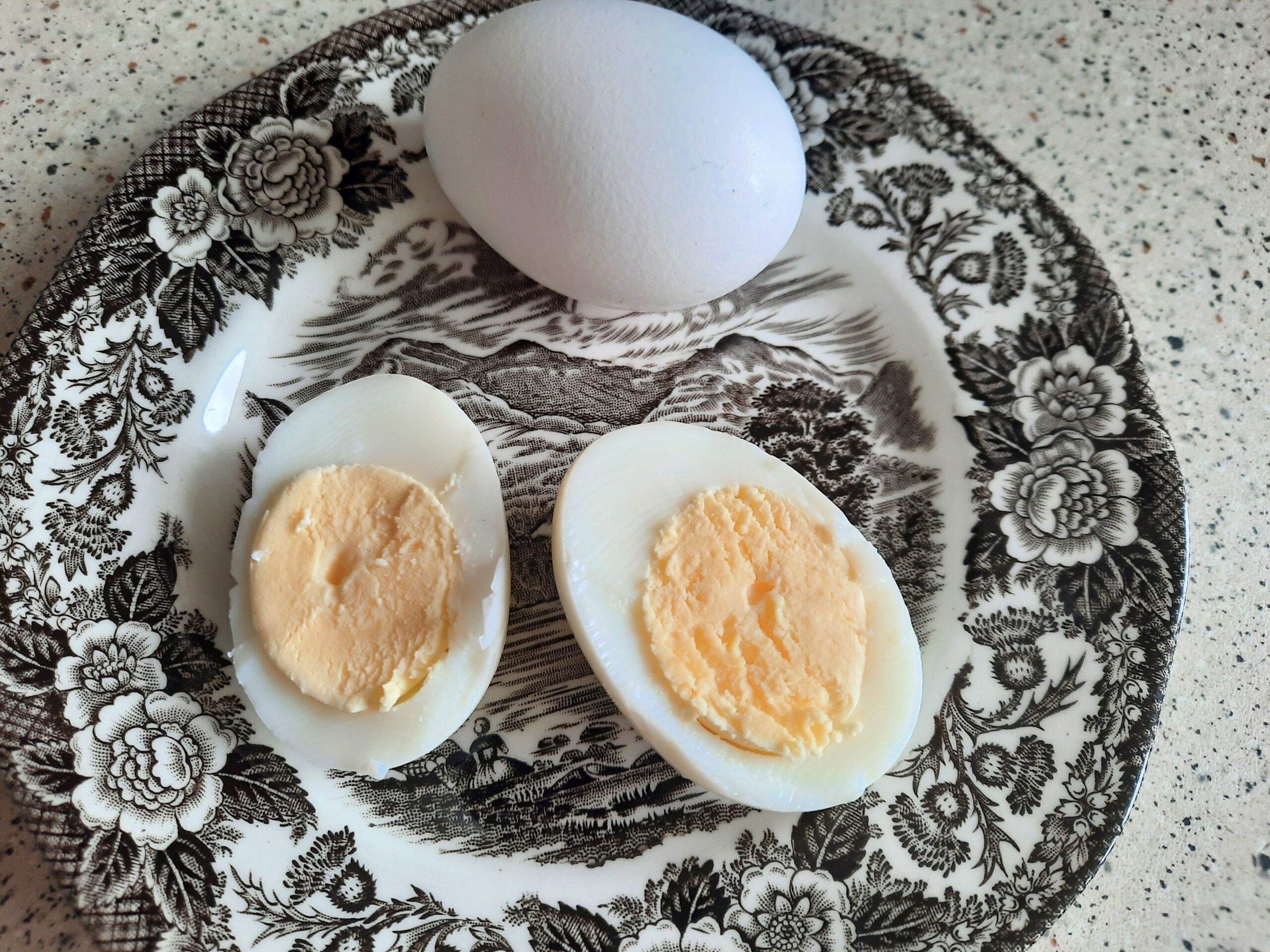 Hard boiled eggs I made in the air fryer. One of the eggs is peeled and sliced in half to show that the egg is completely cooked