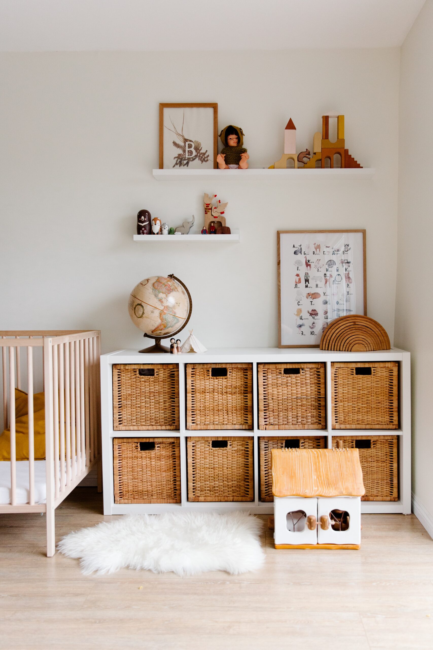 A child's room that includes a cube storage unit with baskets and above the storage unit are wall shelves with toys and decorations. 