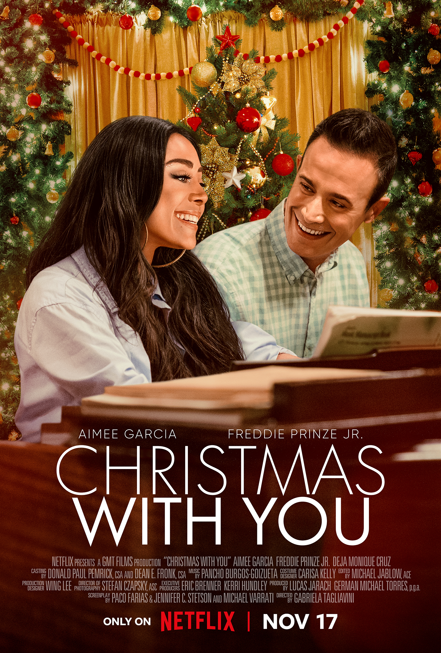 Christmas with You movie poster. The poster shows both Aimee Garcia and Freddie Prinze Jr. sitting at a piano. 