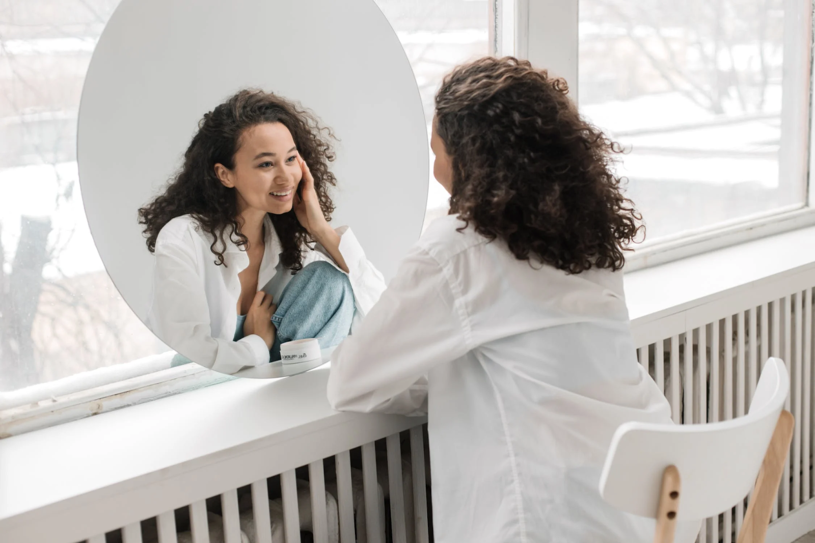 A woman sitting in a chair and looking at yourself in the mirror and smiling
