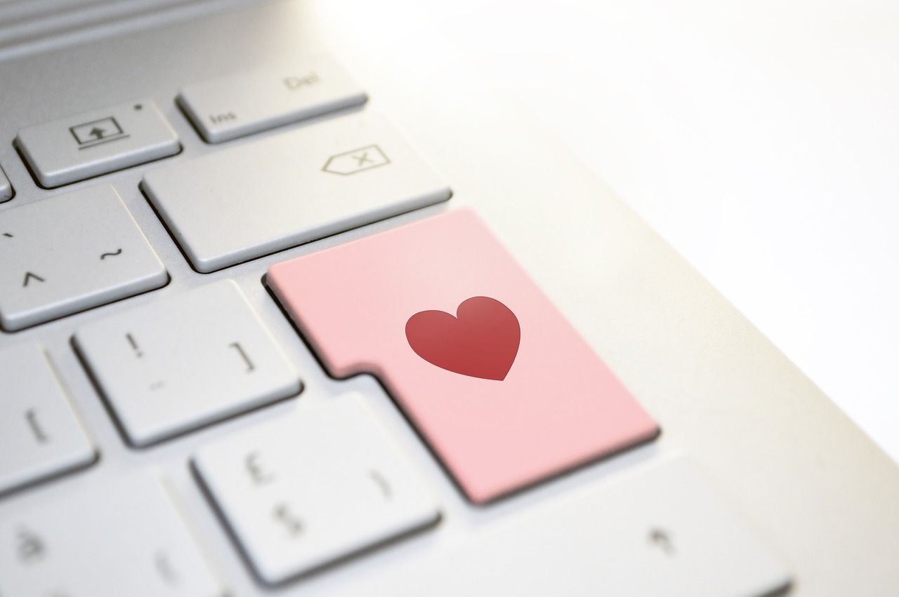 A closeup of a white keyboard with a red heart on the enter key.