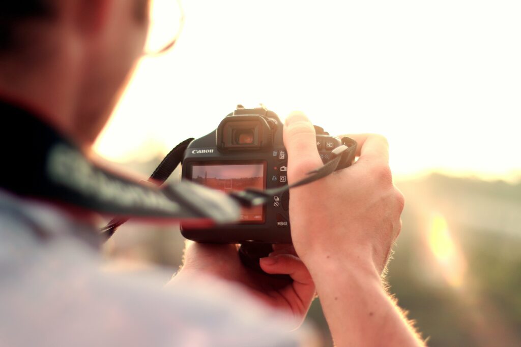 A man holding a black camera and standing in front of the sun. Photography is one of the creative hobbies mentioned in the post.
