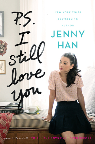 The cover of P.S. I Still Love You by Jenny Han which shows Lara Jean sitting on a bed and looking to her right while wearing a pink short-sleeved shirt and black skirt.