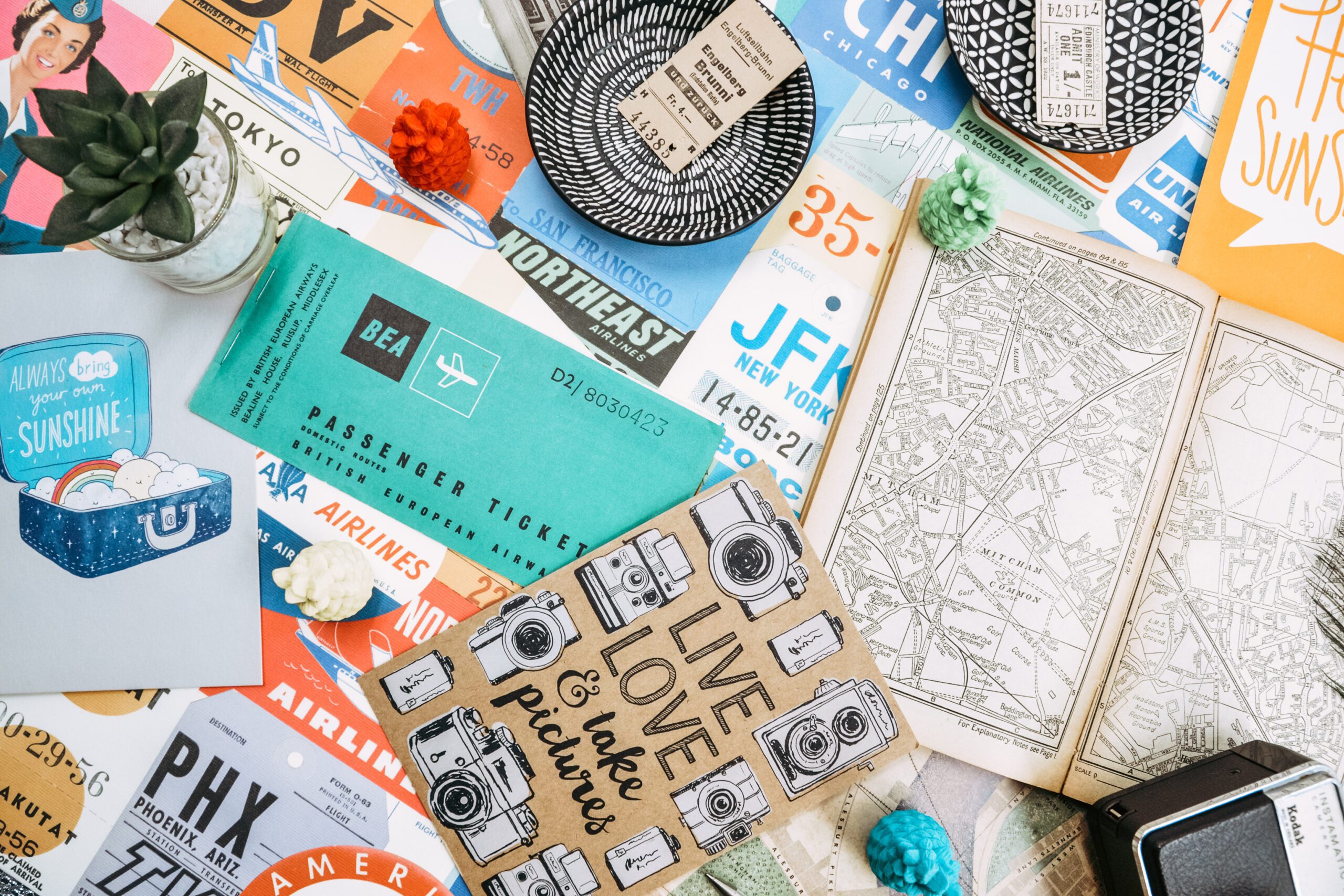 Vintage travel tickets next to a small succulent plant, an open map, and a card that states 'Live Love & take pictures'