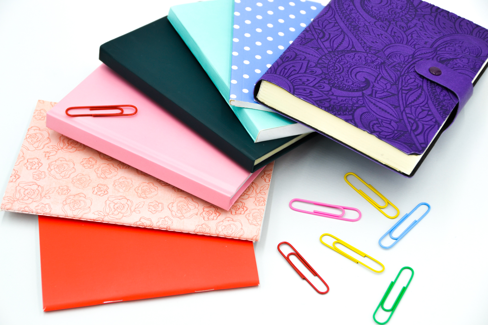 6 multicolored notebooks with multicolored paper clips scattered around