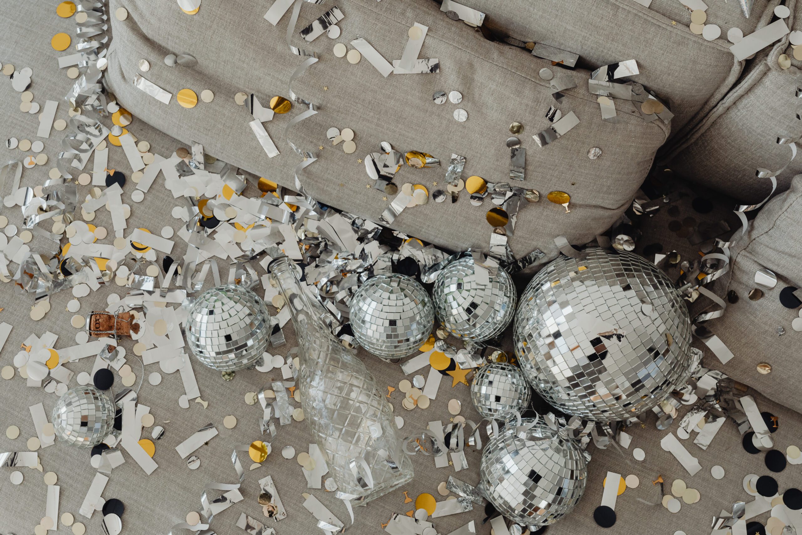 Silver disco balls and confetti on a grey couch