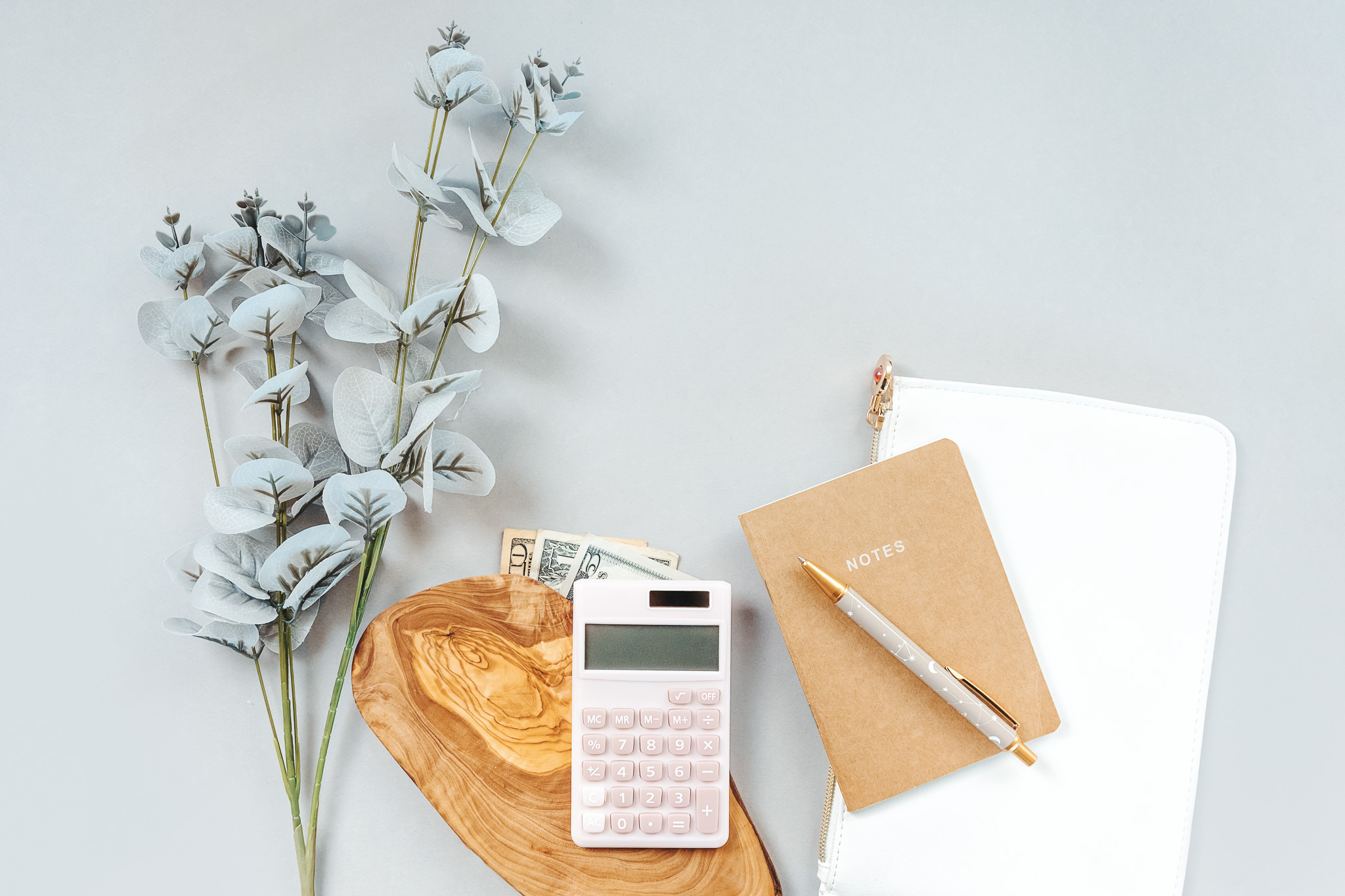 A notebook next to a calculator and dollar bills
