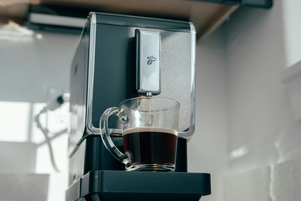 A coffee maker with a clear cup of coffee being filled