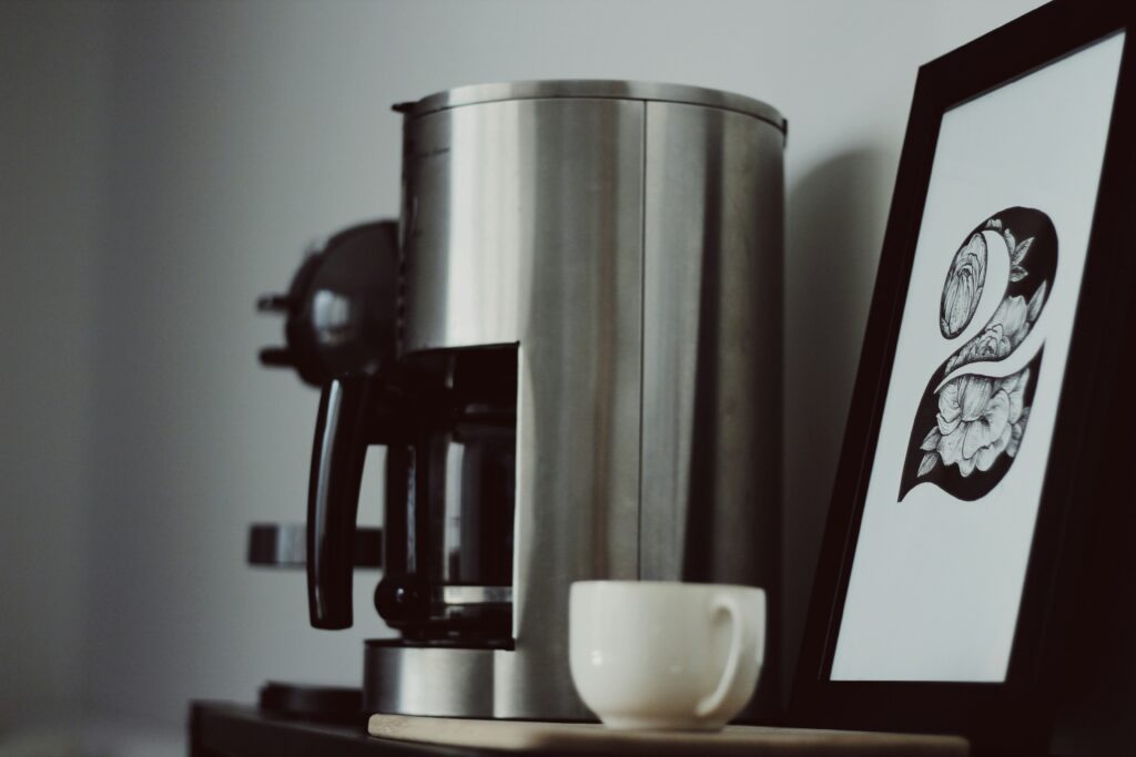 A silver coffee machine next to a white mug