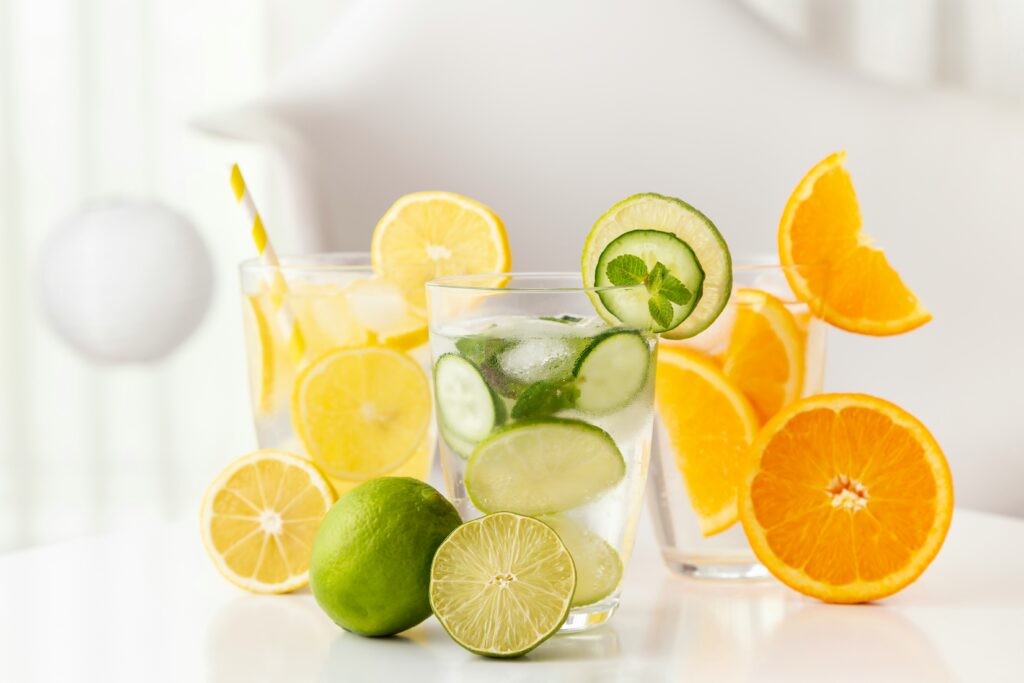 Glasses of water that are filled with cucumber and citrus fruits.