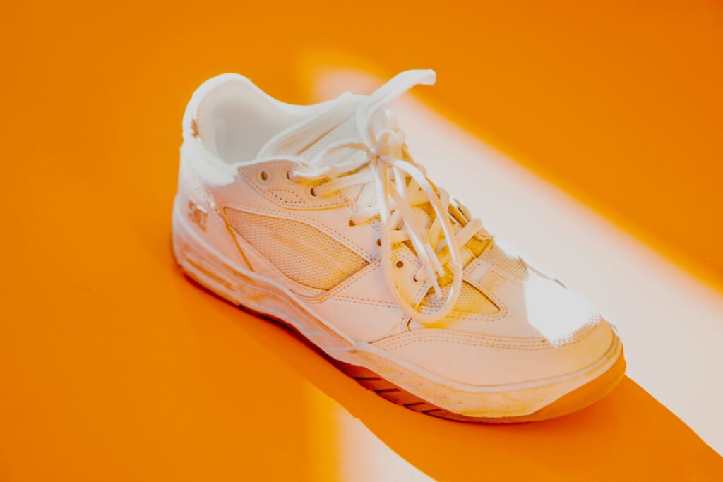 A pair of white sneakers on an orange background
