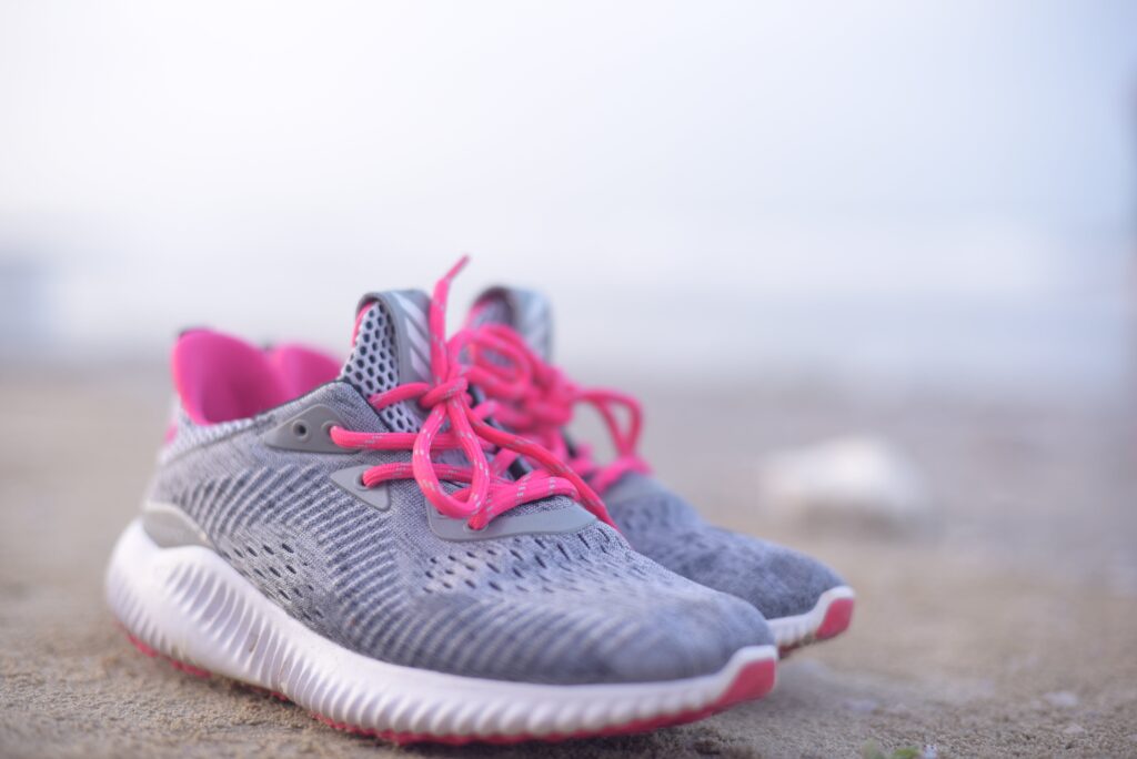 A pair of grey sneakers with pink shoelaces