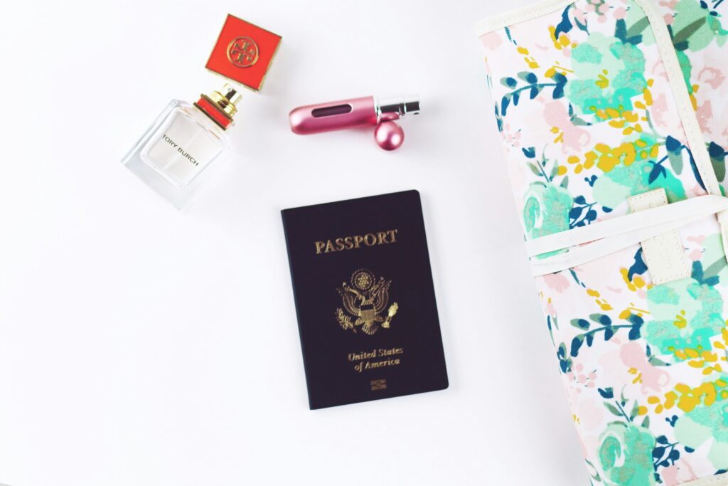 An American passport with a bottle of perfume and a travel sized perfume