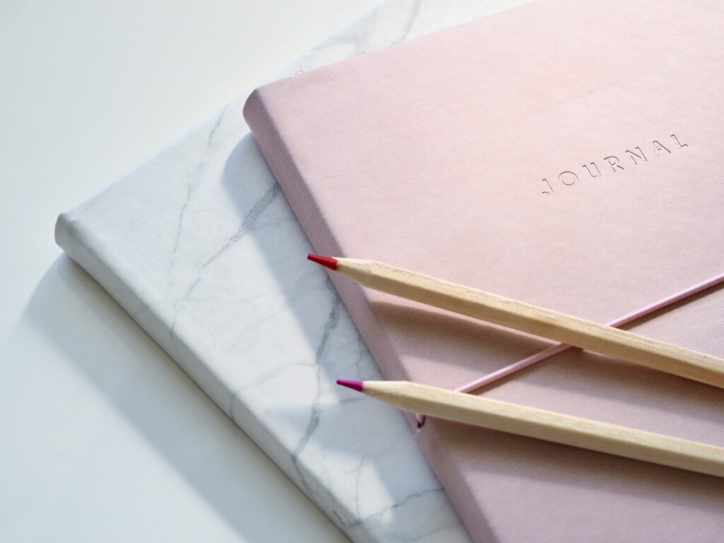 Two journals stacked on top of each each other with colored pencils