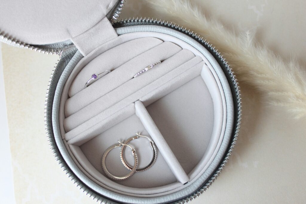A jewellery box with two silver rings and a silver pair of earrings.