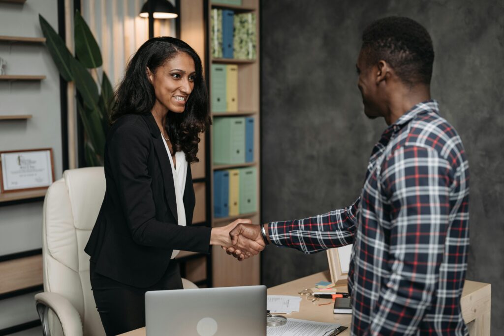 A female lawyer wearing a black suit and shaking hands with a client