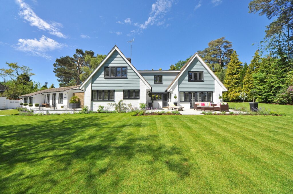A white and grey house with a backyard patio and lawn