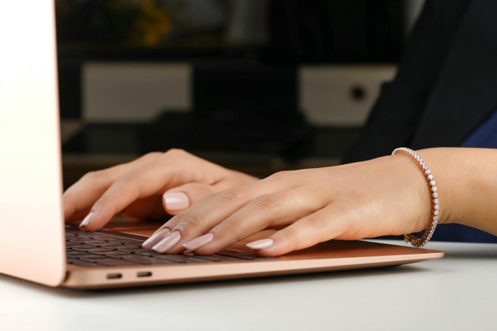 A woman wearing a diamond bracelet while typing on a laptop