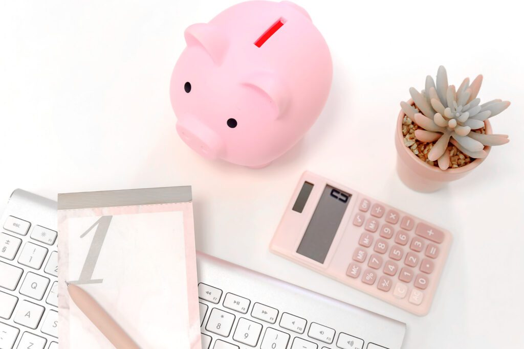 A calculator with a piggy bank and notepad.