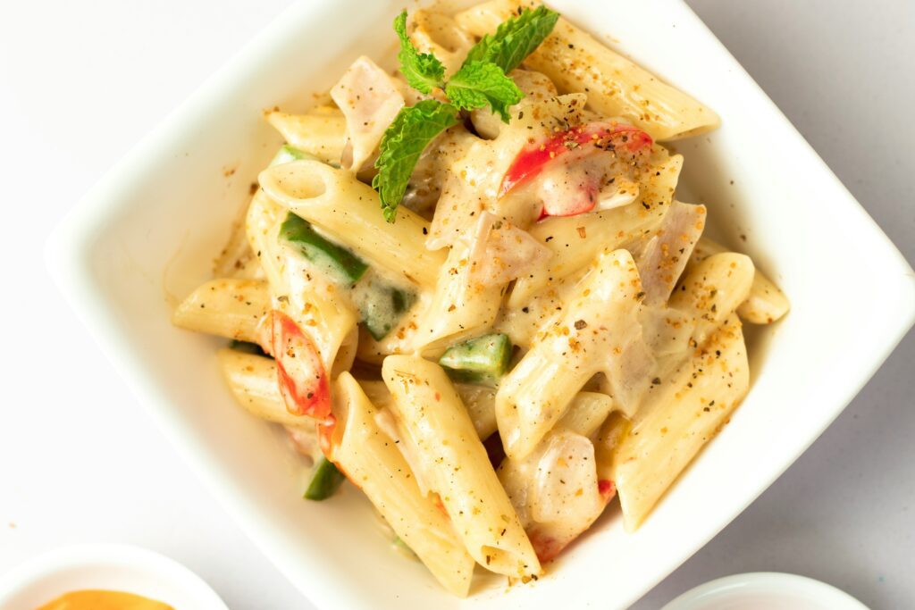 A white bowl of penne pasta with a cream sauce