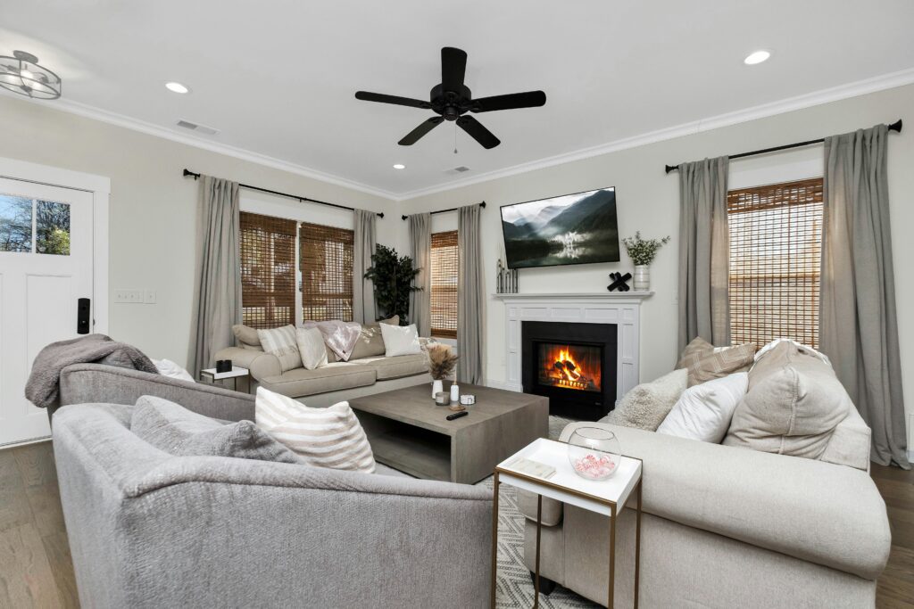 A living room with two grey couches and chairs and a black ceiling fan