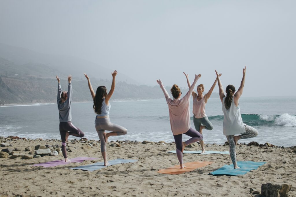 A group of 5 people doing yoga on the beach