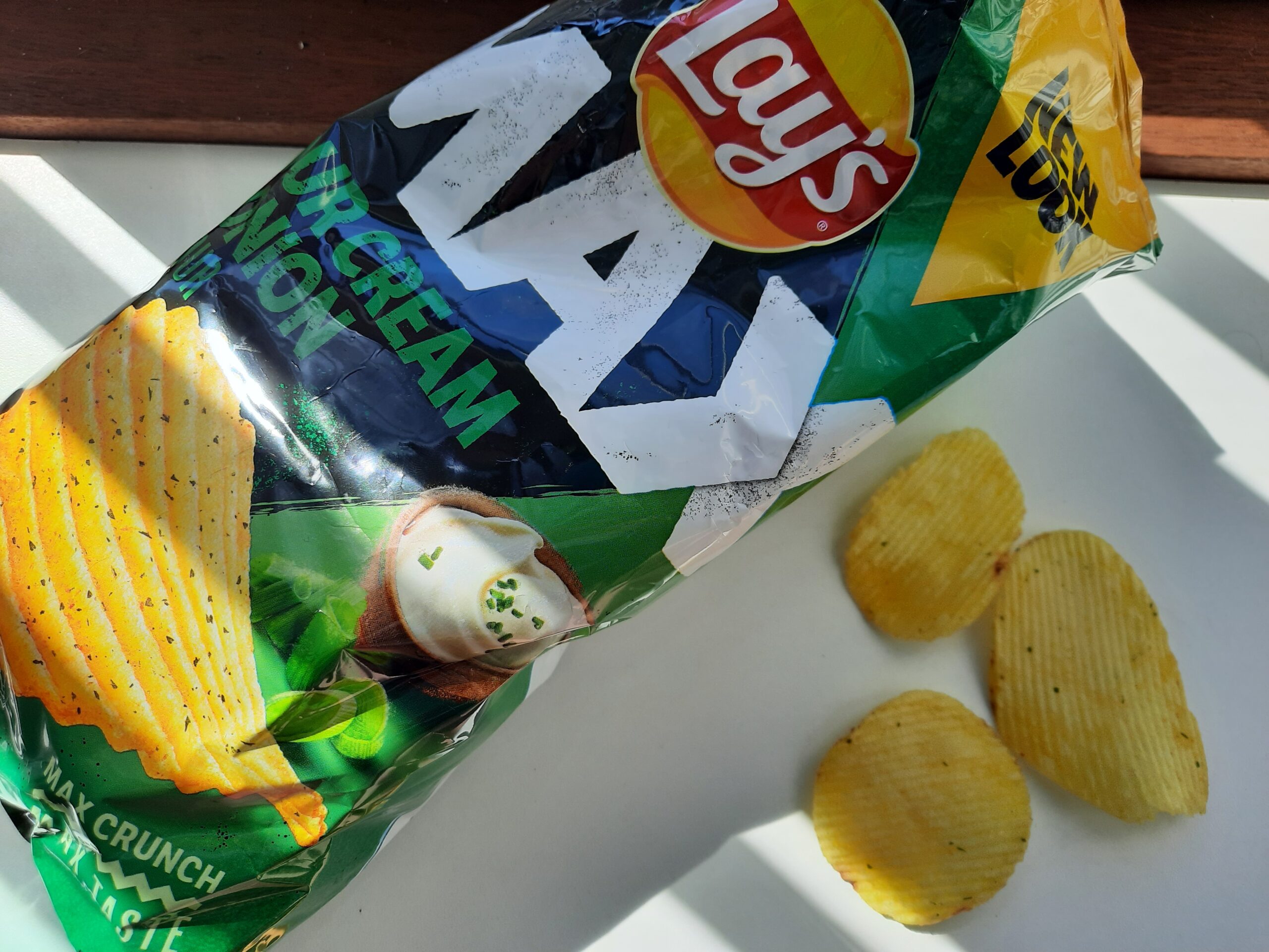 The bag of the Lay's Max Sour Cream Onion next to a few of the chips.