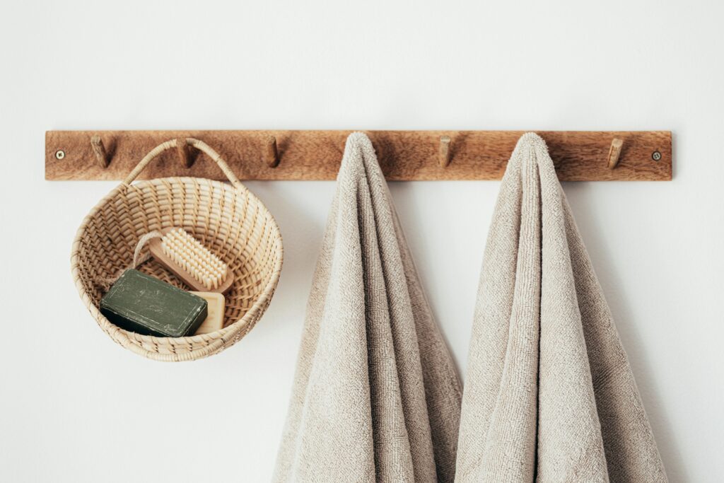 Two beige towels hung on a rack next to a basket with soap bars.