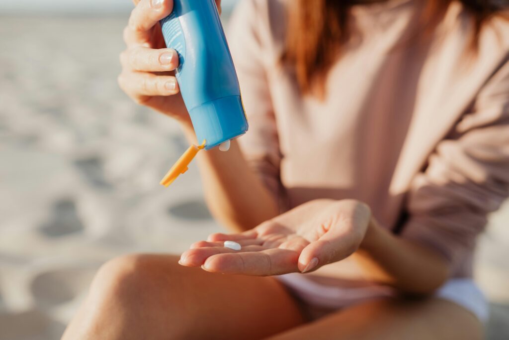 A woman putting sunscreen on her hand on the beacnh