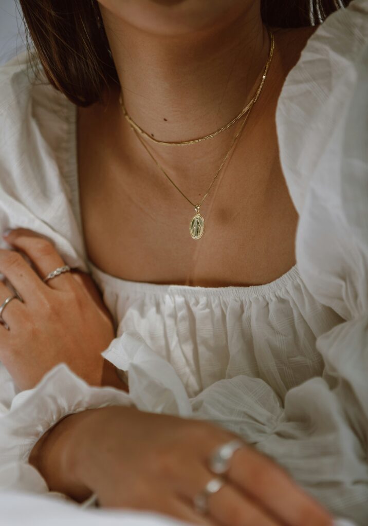 A woman wearing a square neck white dress with a long necklace