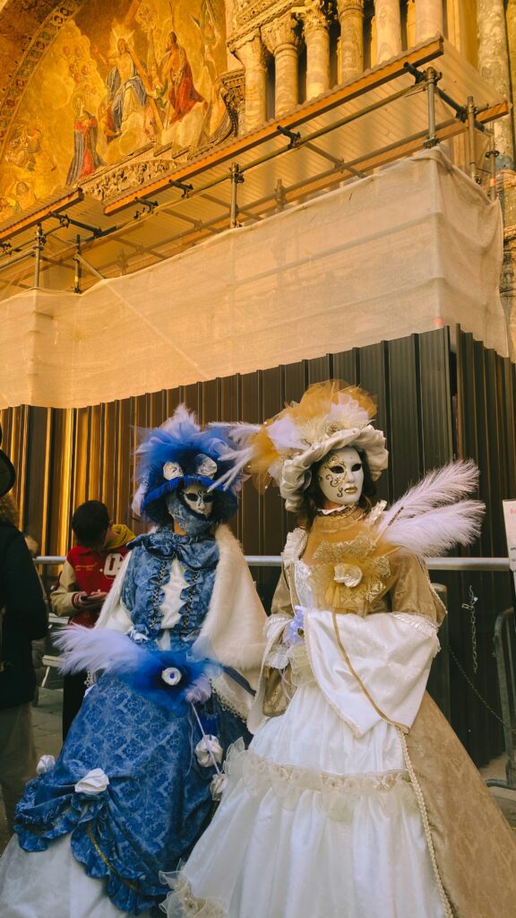 Two individuals wearing costumes and masks during the Carnevale di Venezia festival in Italy