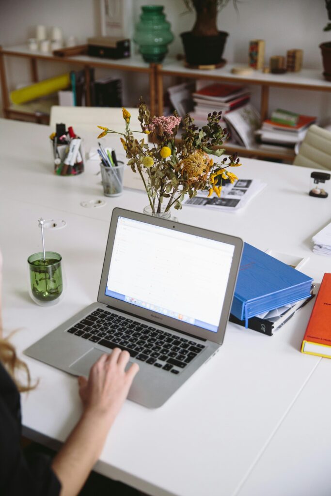 A laptop on a table next to books and documents
