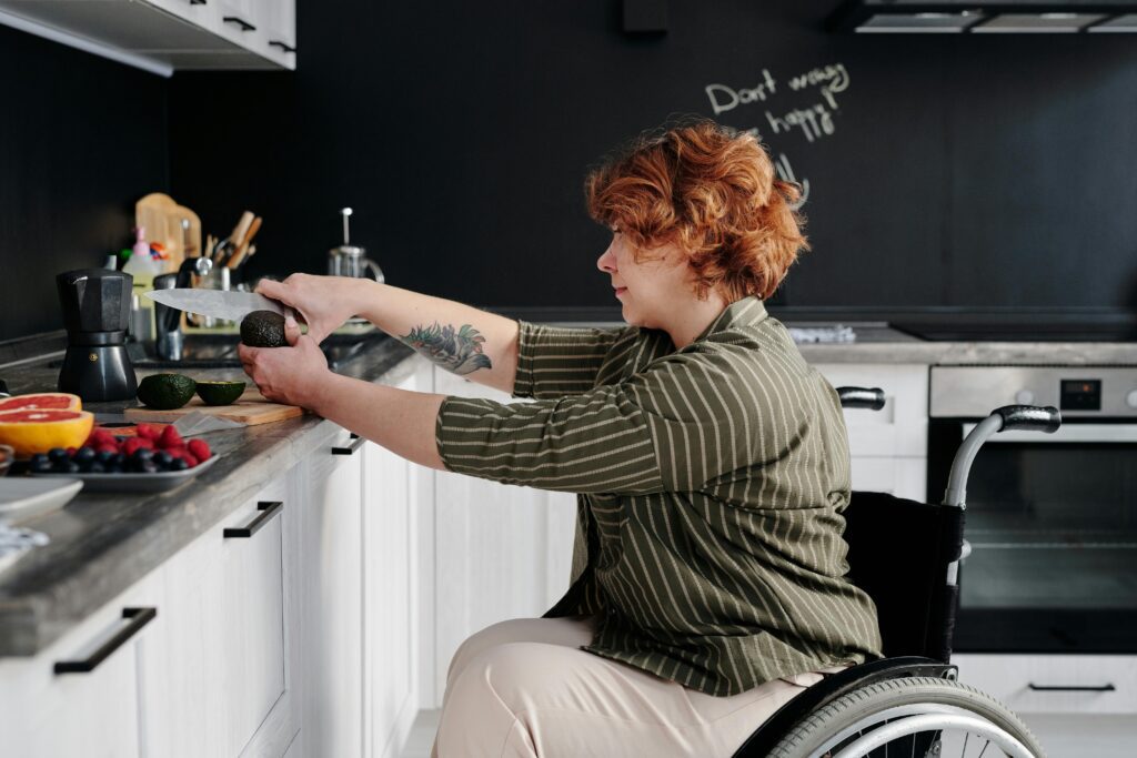 A woman in a wheelchair cutting an avocado in an accessible kitchen