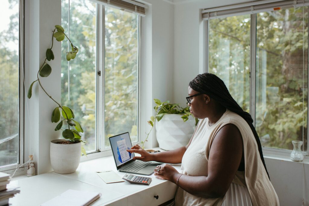 A woman working at a laptop in a home office