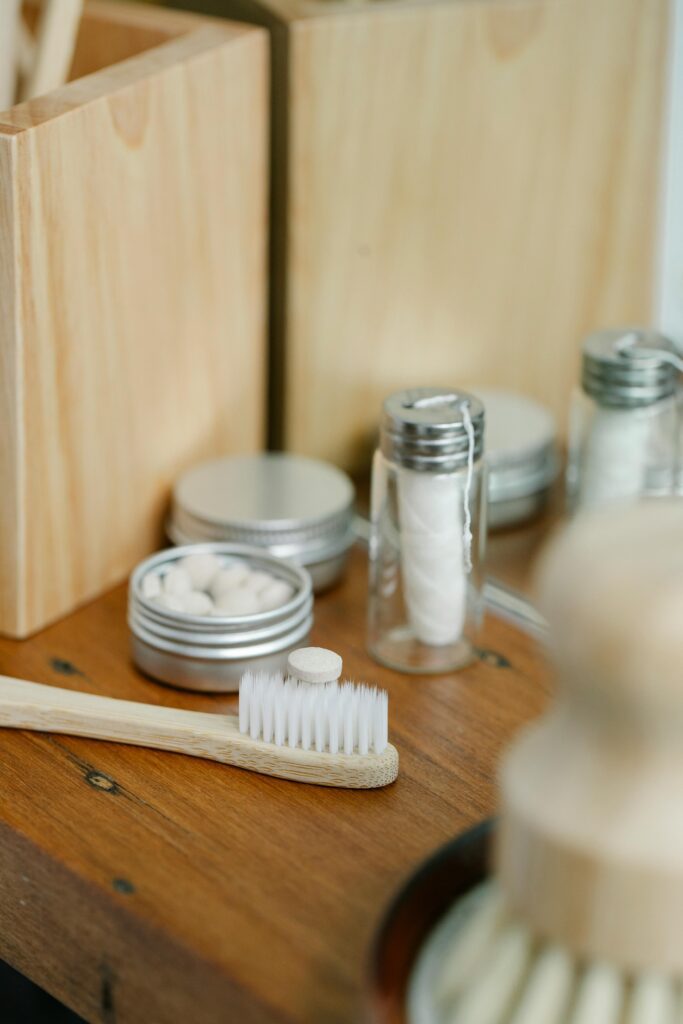 A toothbrush next to a tin with toothpaste tablets and a jar of floss.