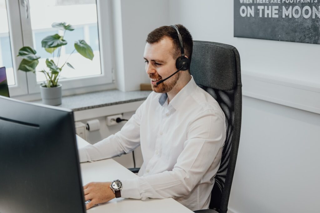 A man wearing a headset is seated at a desk, using a computer, demonstrating computer telephony integration.
