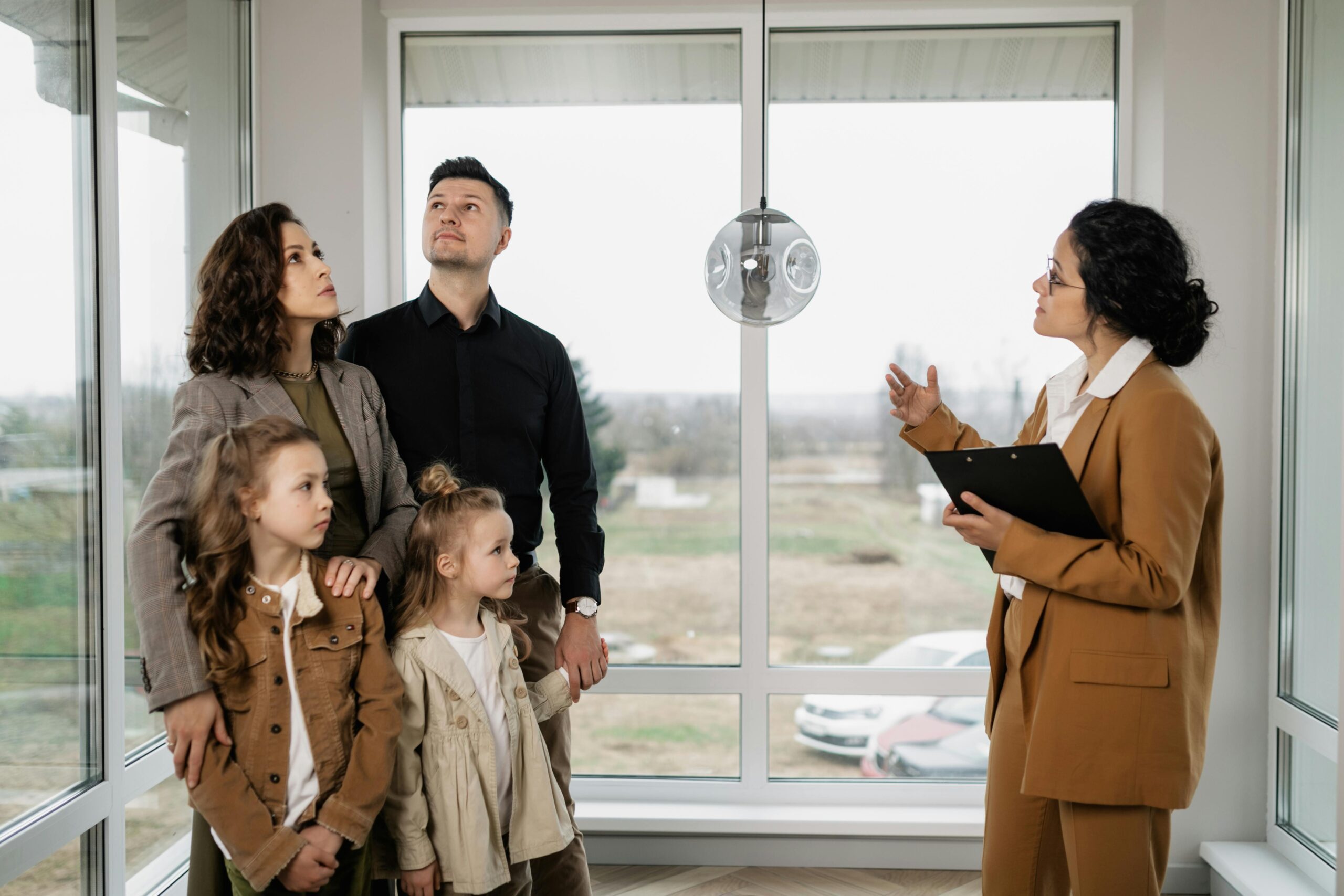 A family with a mother, father, and two daughters touring a home with a real estate agent.