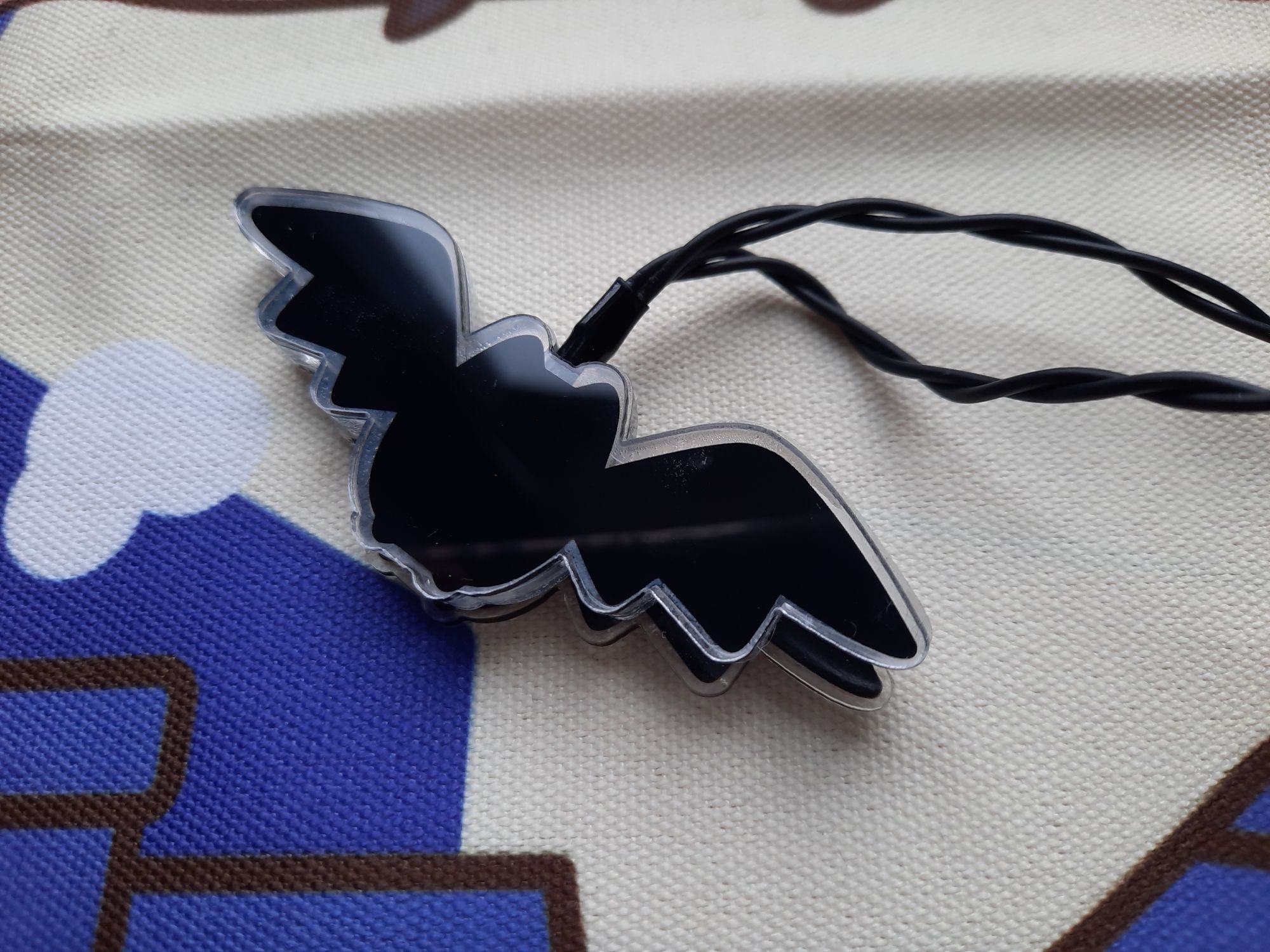 A close-up of one of the bats on the string lights which shows the back wing is crooked and misaligned with the front wing