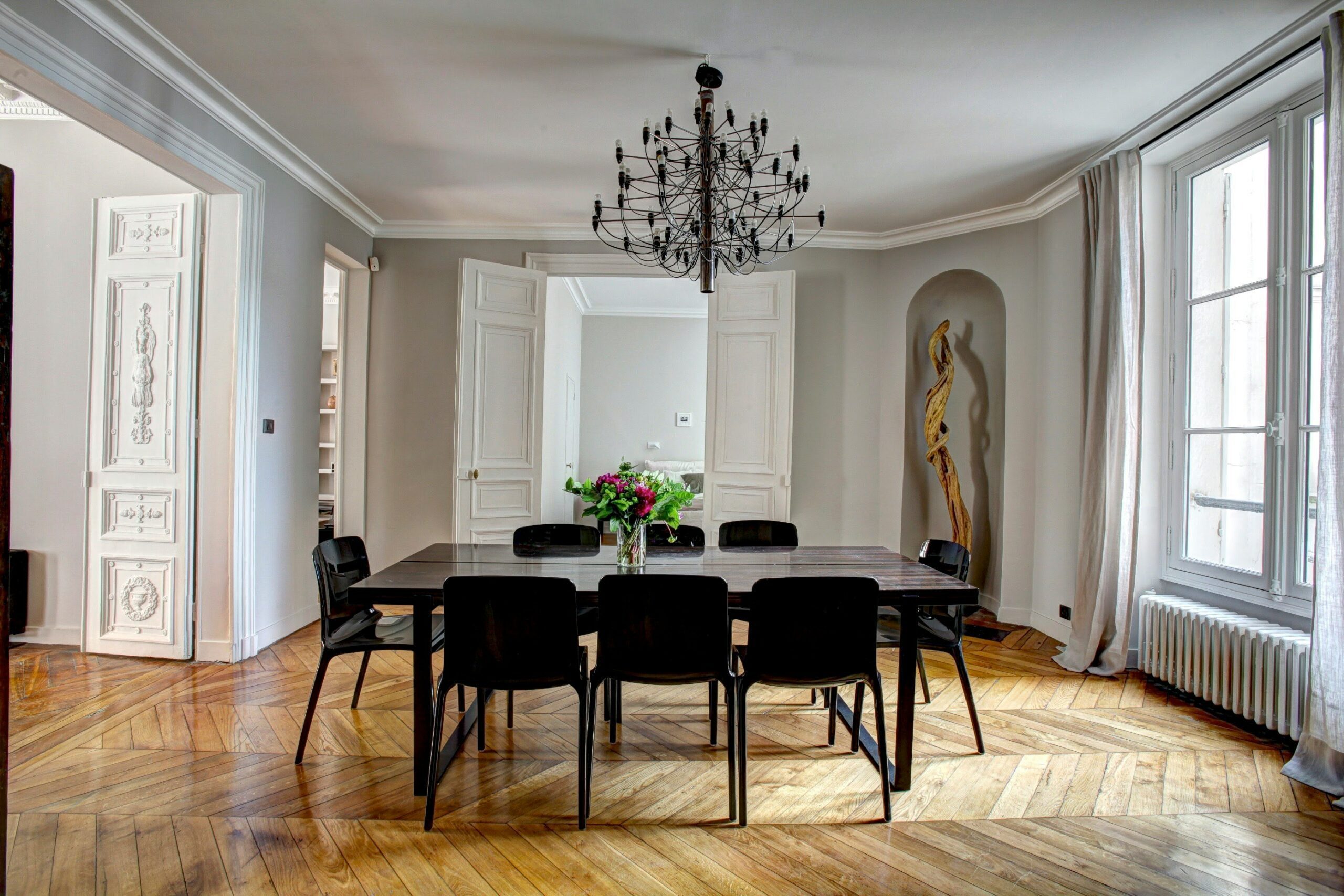 A dining room with grey walls, a dark wooden table, and black metal chairs.