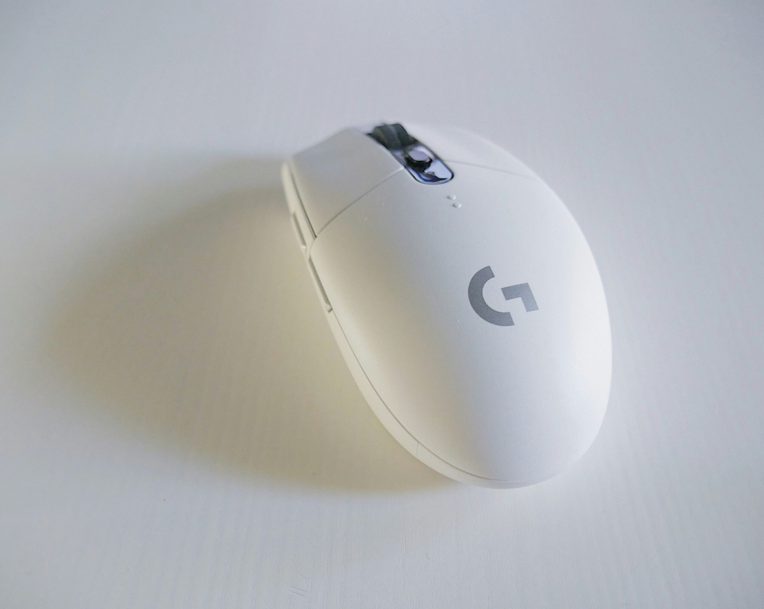 A close up of a white Logitech gaming mouse on a plain white background