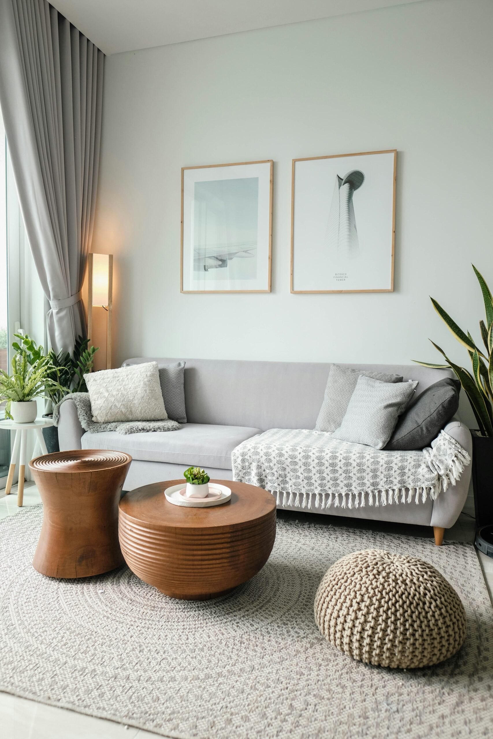 A well-lit living room with a grey sofa, bronze coffee table, and a cream poof