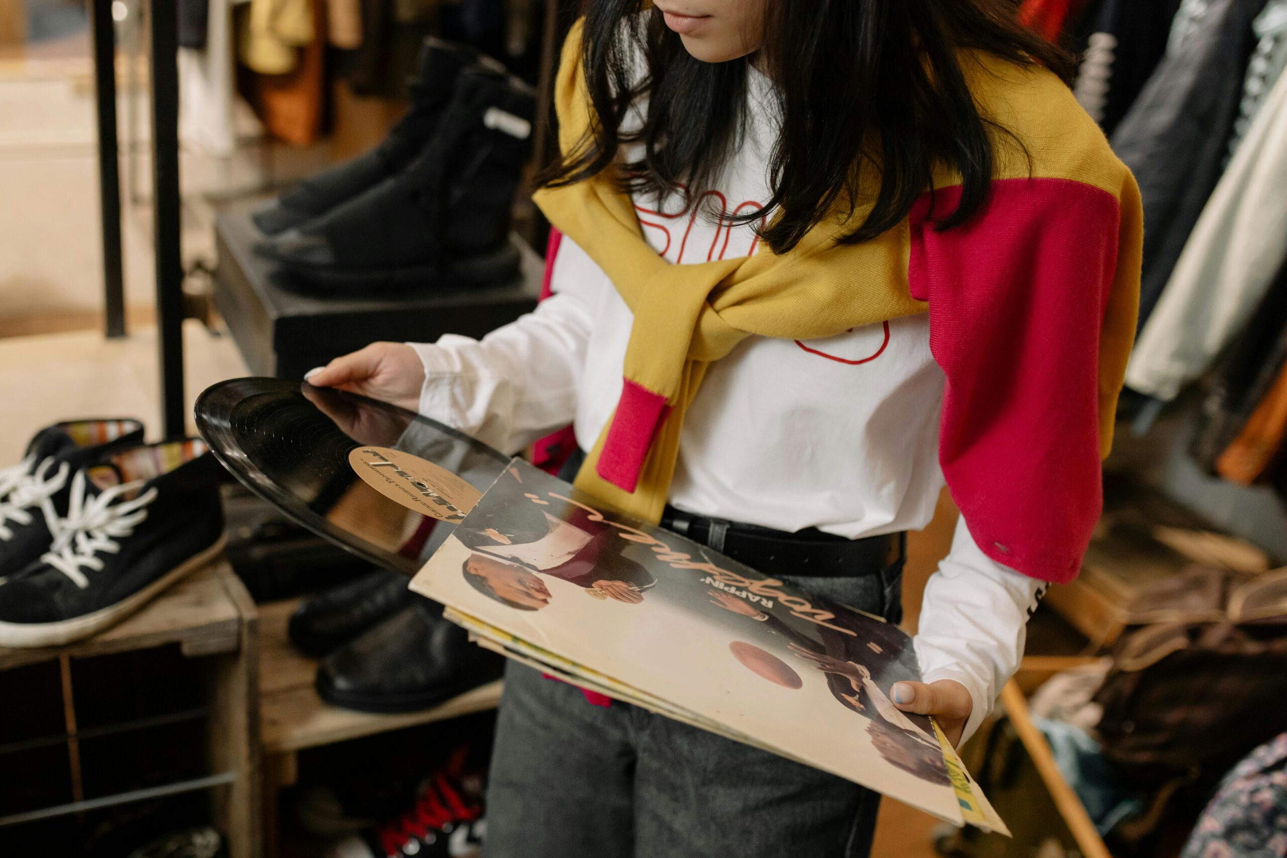 A woman looking at a vinyl record in a thrift store