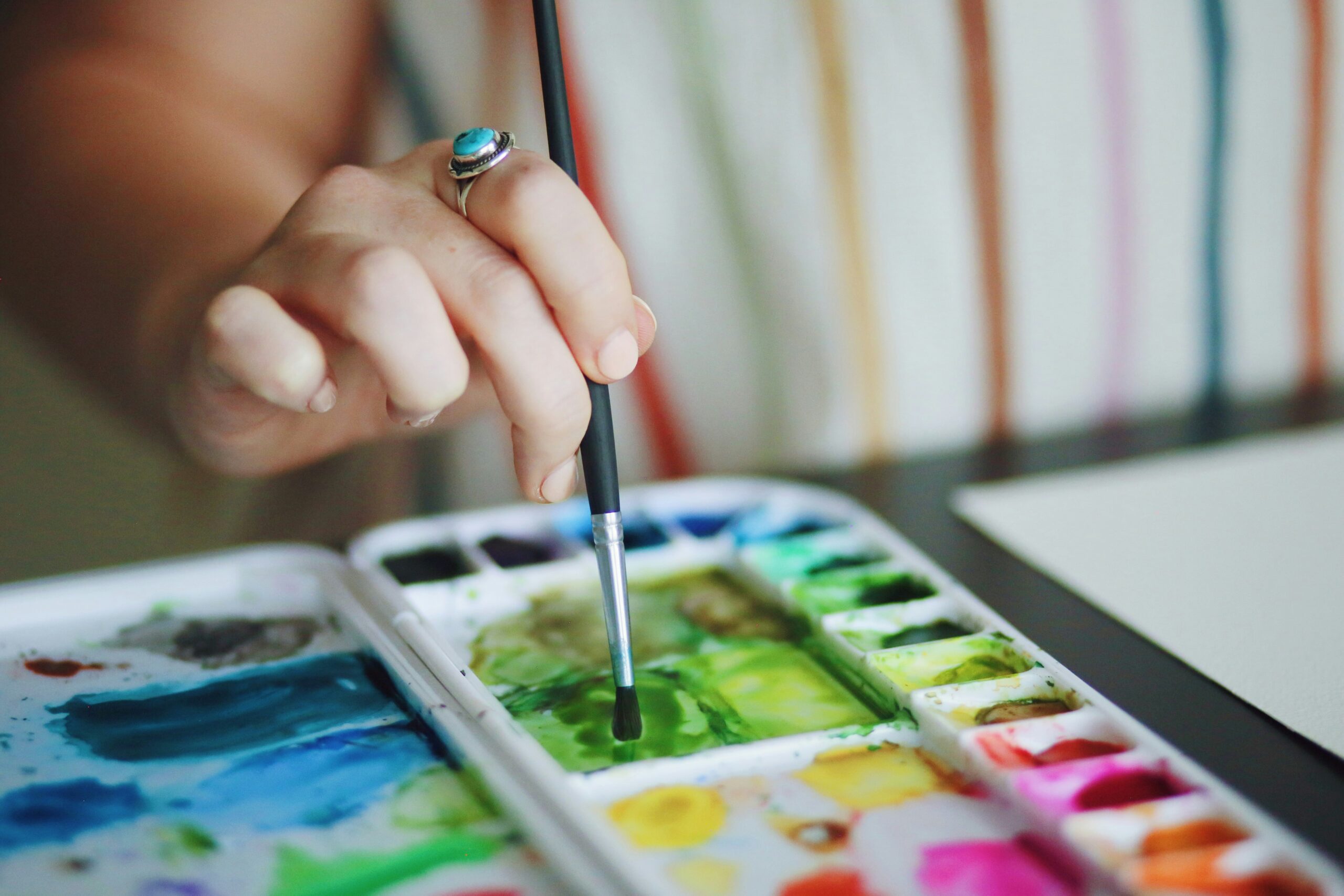 A closeup of a woman using a water color palette