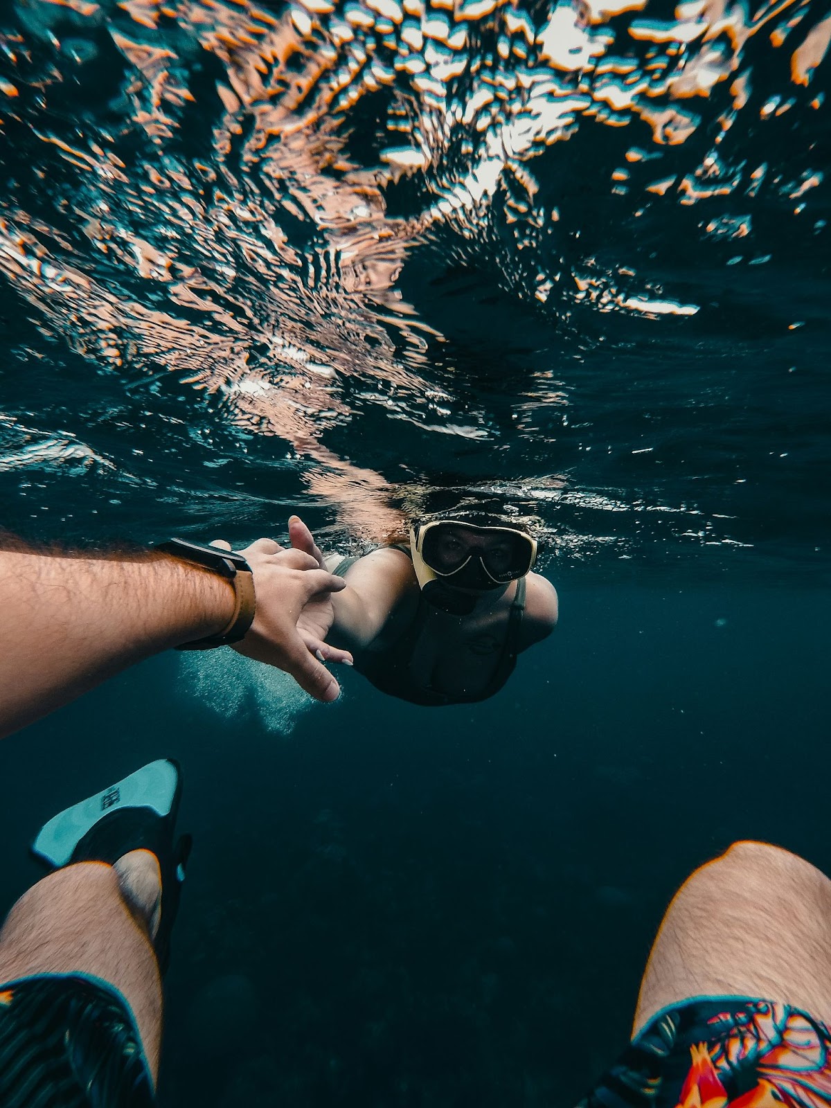 A couple holding hands and snorkeling in the water